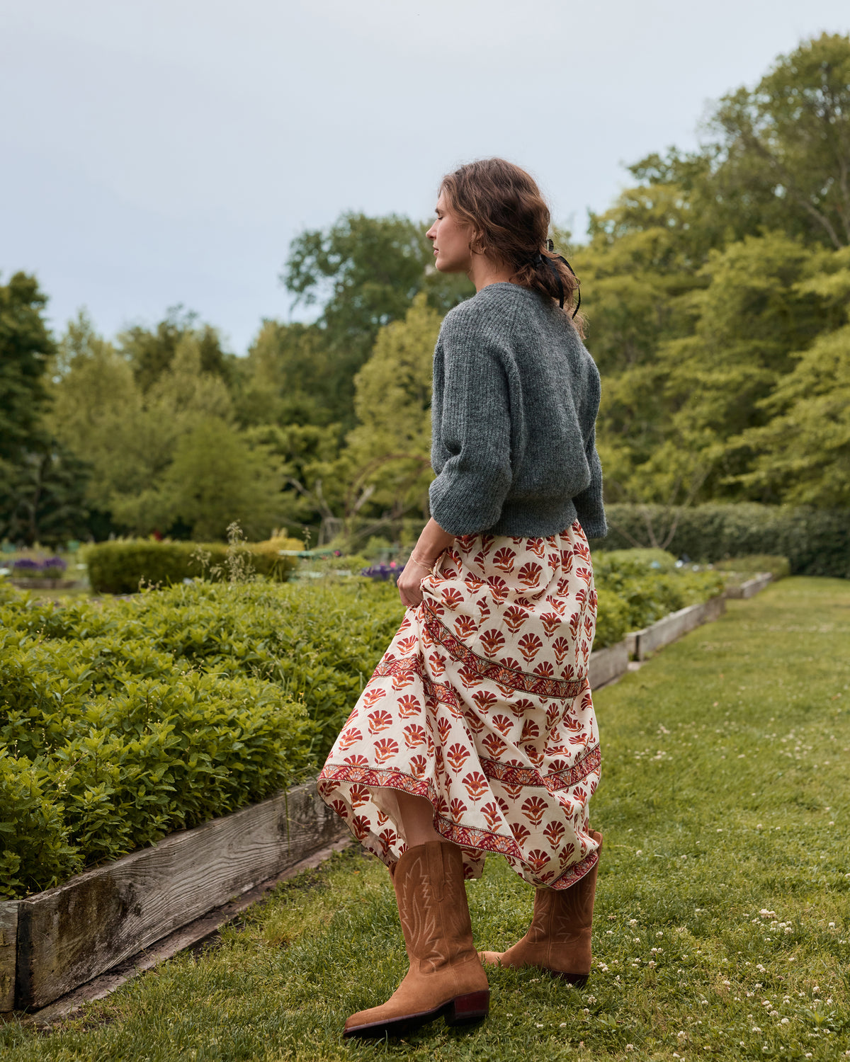 Back view of the cream Sierra Bloom Carry On Skirt showing its red floral print, tiered border bands, and flowing hem.