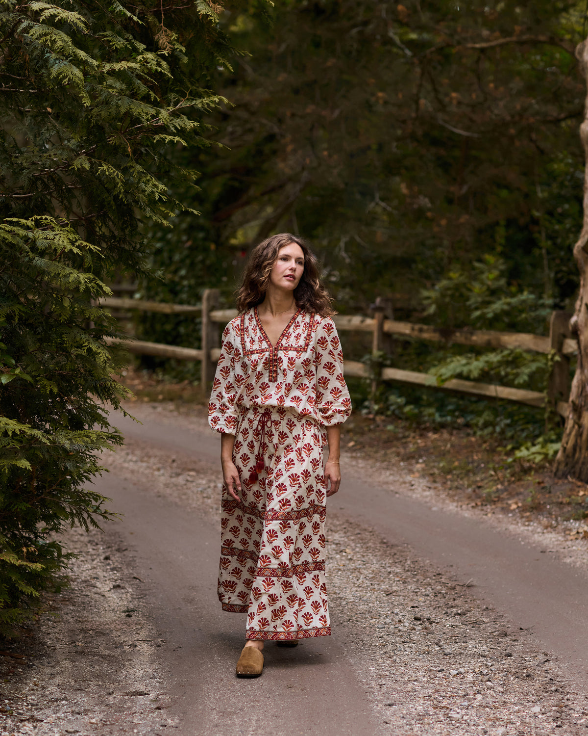 Full-length front view of the Sierra Bloom floral-print blouse and long skirt set on a wooded path