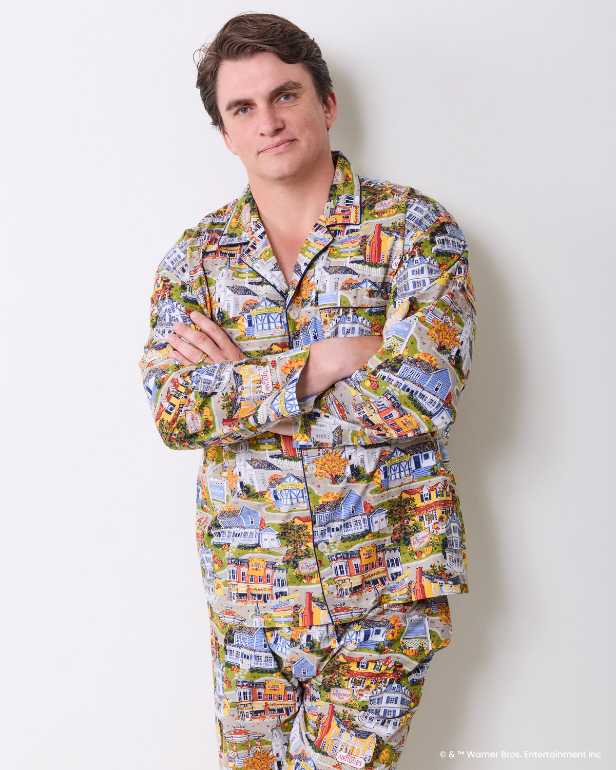 Person wearing a long-sleeve pajama shirt and pants with a colorful Stars Hollow illustrated print.