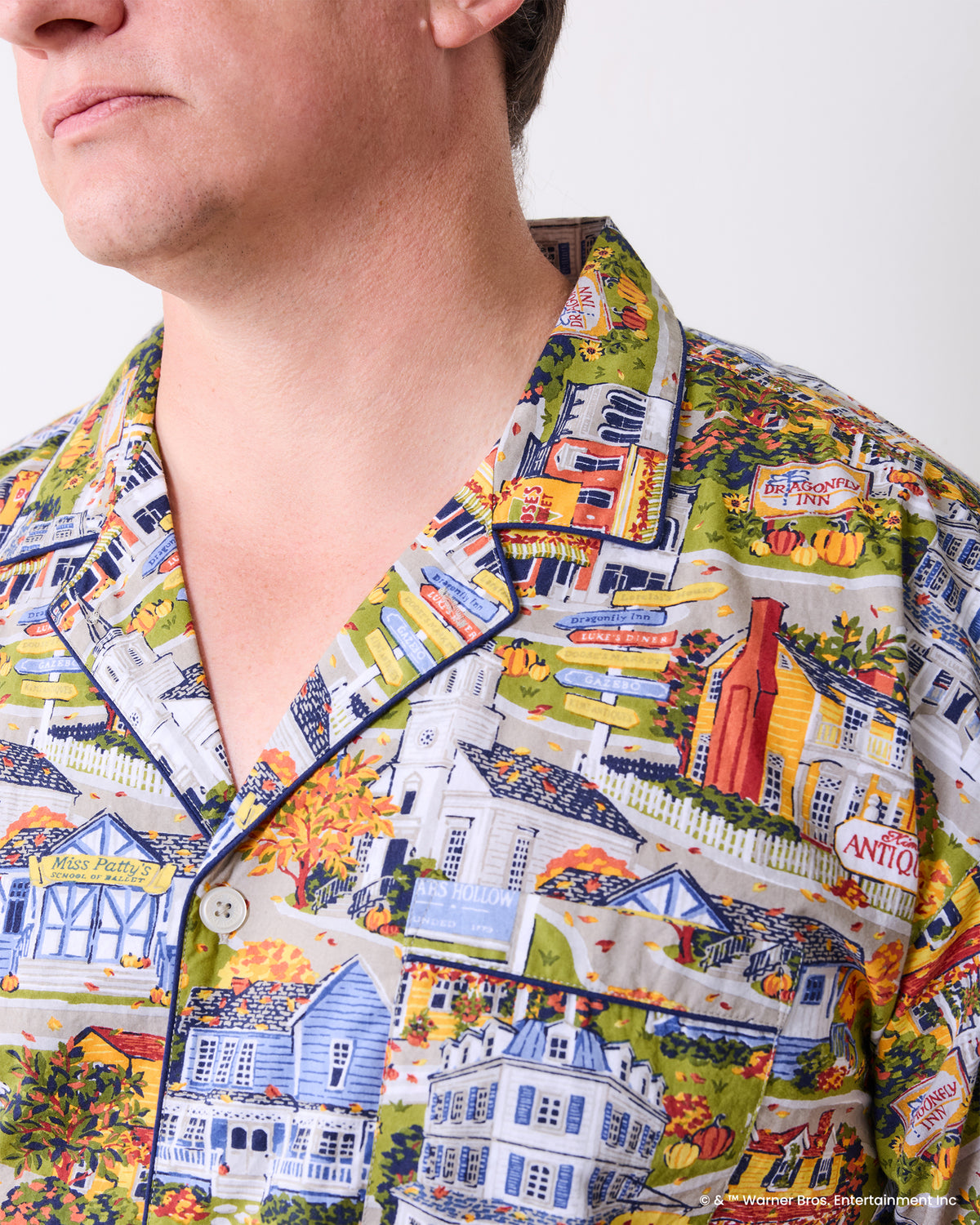 Close-up of the pajama shirt collar, dark piping, button, and colorful Stars Hollow town print.