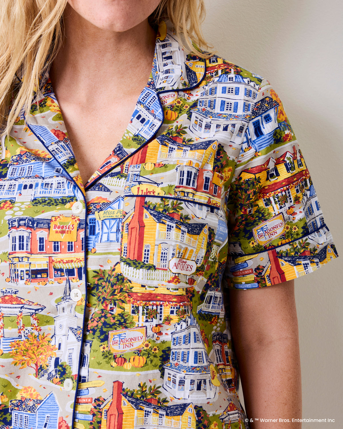 Close view of the short-sleeve button-down pajama top in the Stars Hollow town print, showing the collar, buttons, and chest pocket.