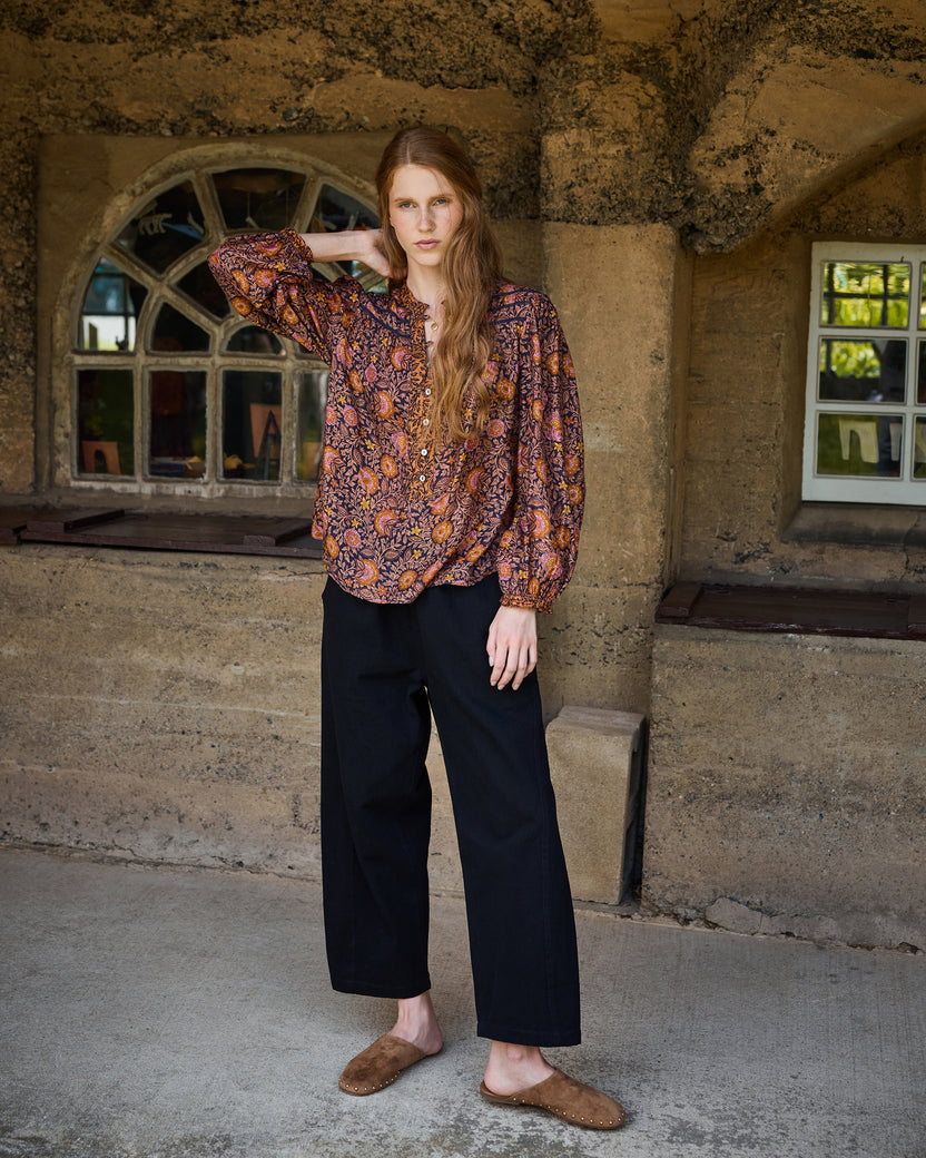 Full-length view of the Sunset Vine Evelyn blouse with long sleeves and gathered cuffs, paired with black wide-leg pants.
