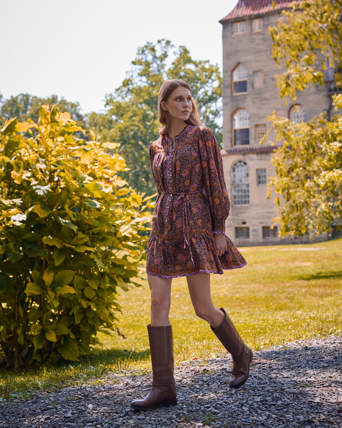 Three-quarter view of the Sunset Vine Soleil Dress showing the floral print, long sleeves, button front, tie waist, and tiered skirt.