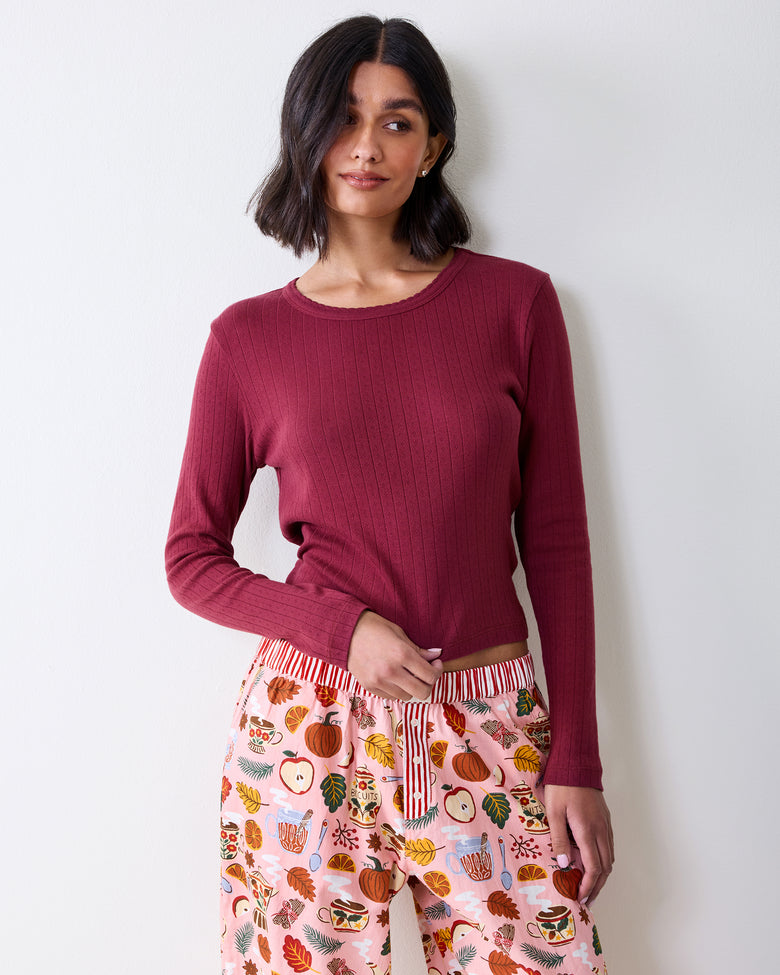 Upper front view of printed pajama pants showing the striped waistband and button fly beneath a long-sleeve top.