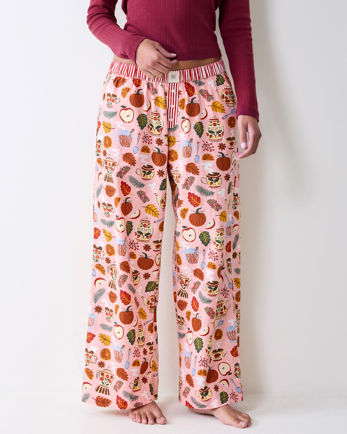 Front close-up of printed wide-leg pajama pants showing the striped waistband, button fly, and patterned legs.