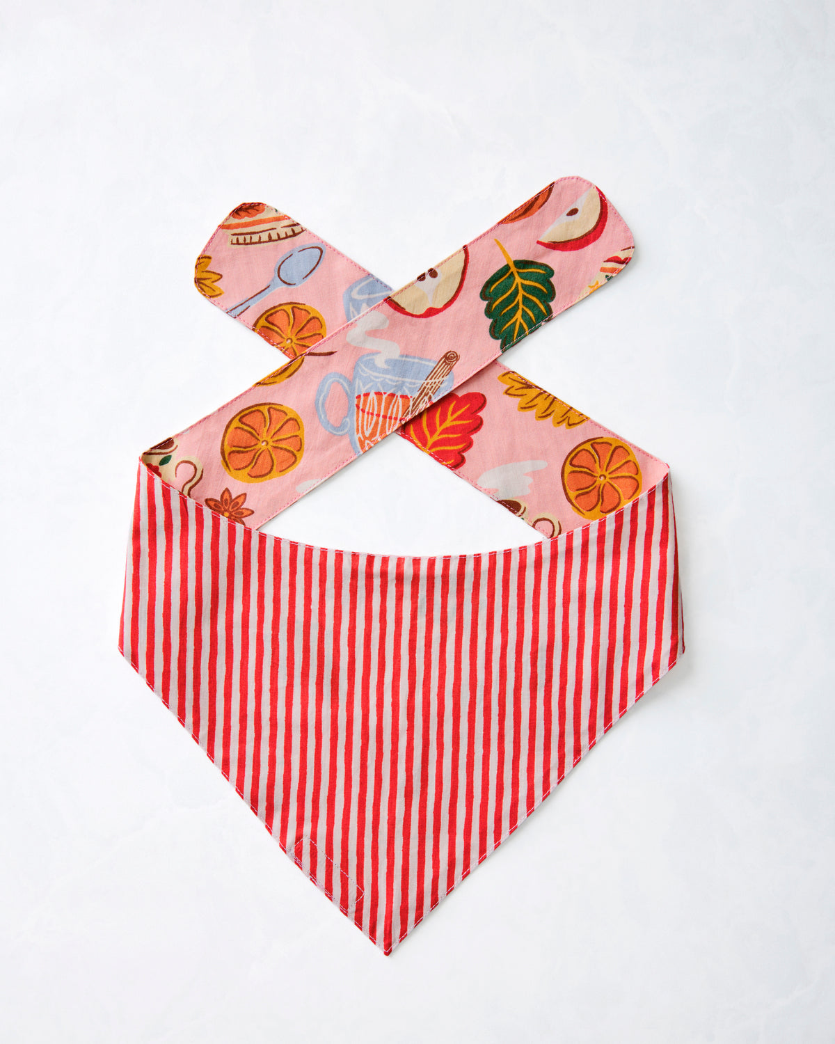 Reverse side of a pet bandana displayed flat with red-and-white vertical stripes and pink printed tie straps.