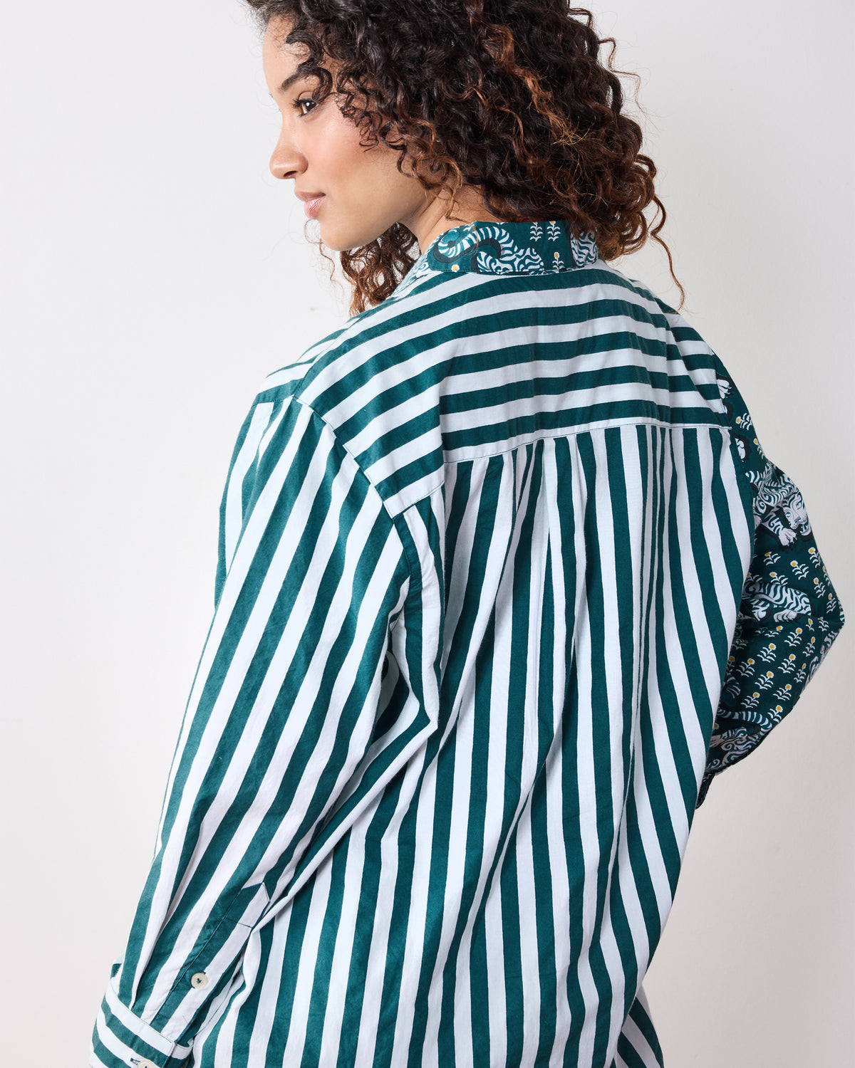 Back view of the Tiger Queen button-down shirt showing the green-and-white striped back, yoke, pleat, and tiger-print sleeve panel.