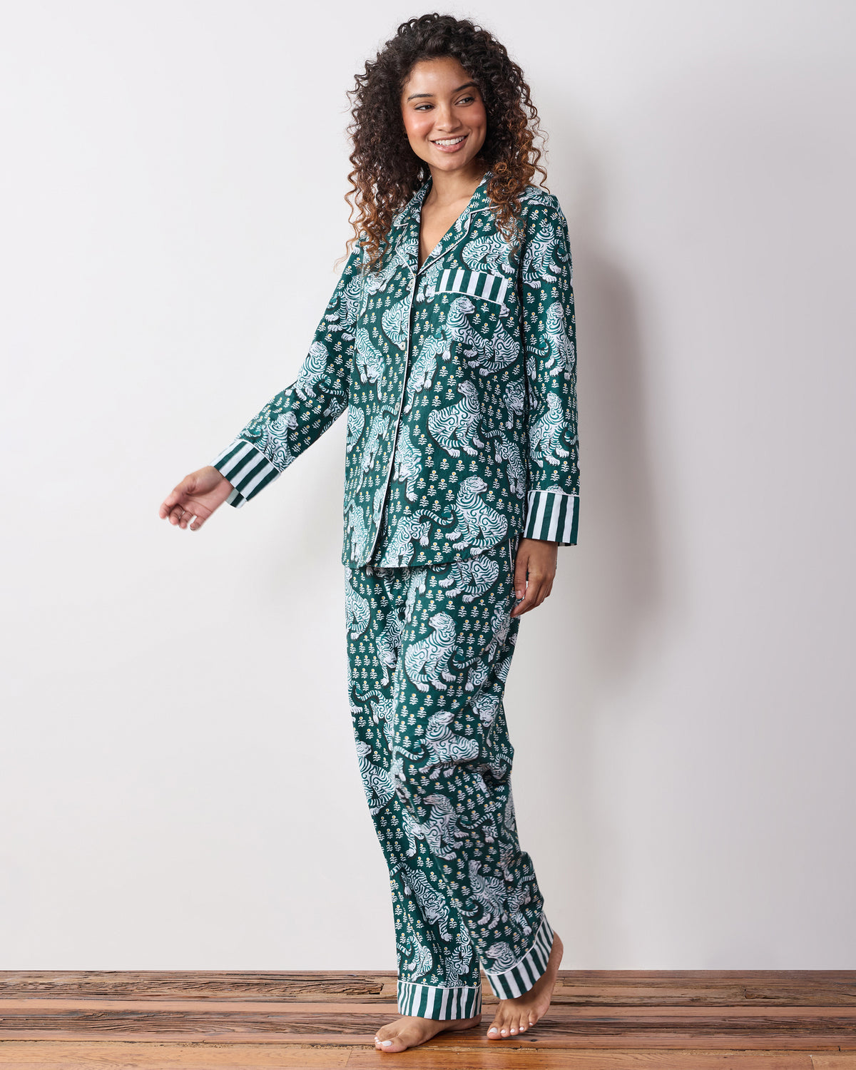 Three-quarter view of a person wearing the Game Day Green Tiger Queen long pajama set with a button-down top, drawstring pants, and striped cuffs.