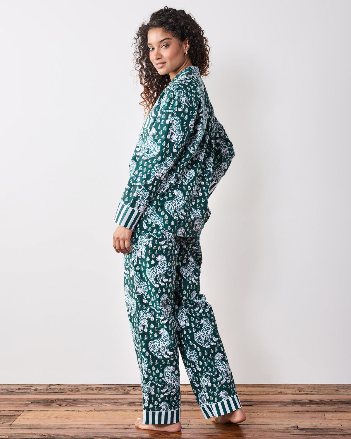 Back view of a green long-sleeve tiger-print pajama set with striped cuffs and trouser hems.