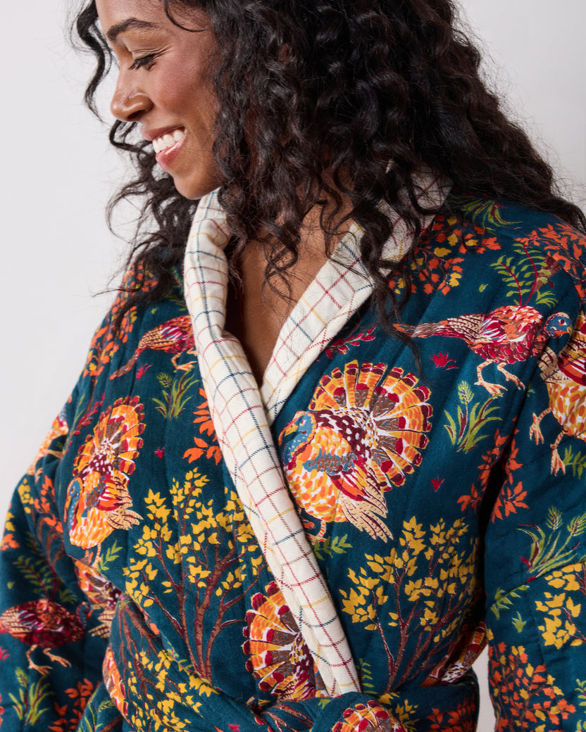 Close-up of a navy Turkey Trot robe with colorful turkey-and-floral print, contrasting plaid shawl collar, and waist tie.