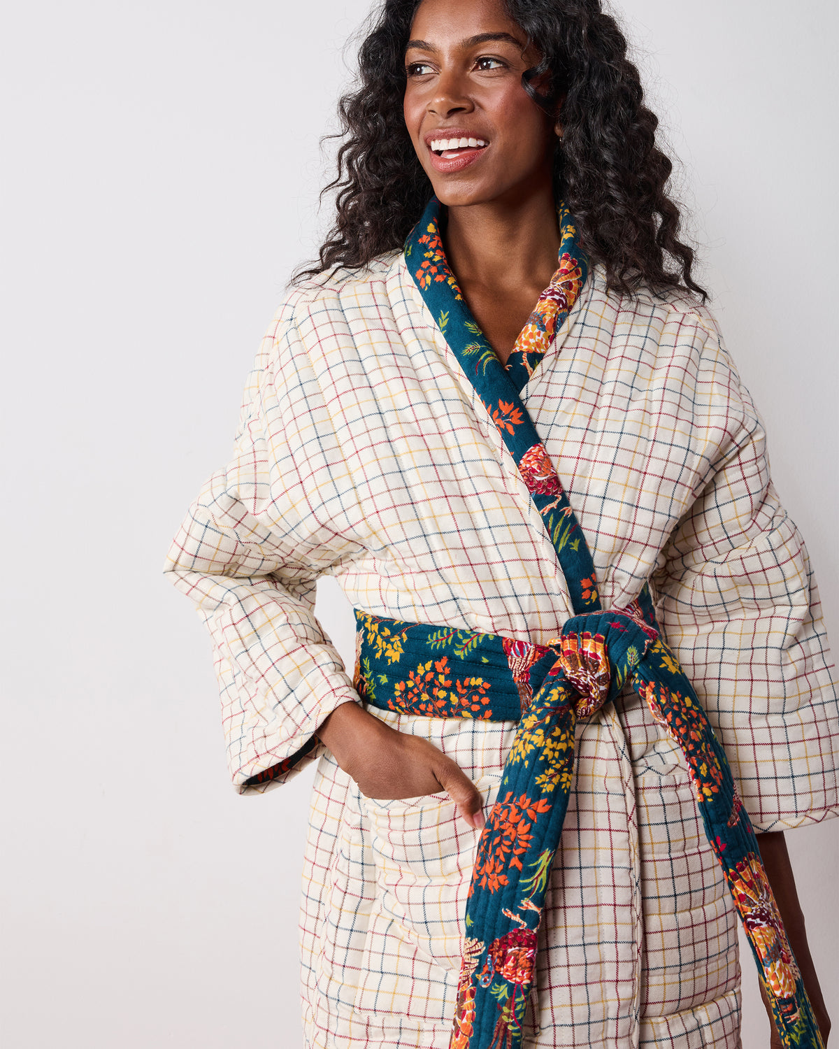 Close-up of the reversible robe’s cream plaid side with a navy printed shawl collar, belt, and trim.