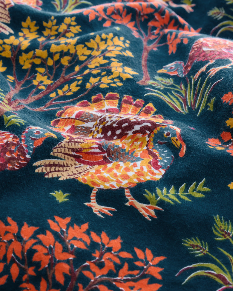 Close-up of the Turkey Trot print featuring illustrated turkeys, trees, foliage, and grasses on navy fabric.