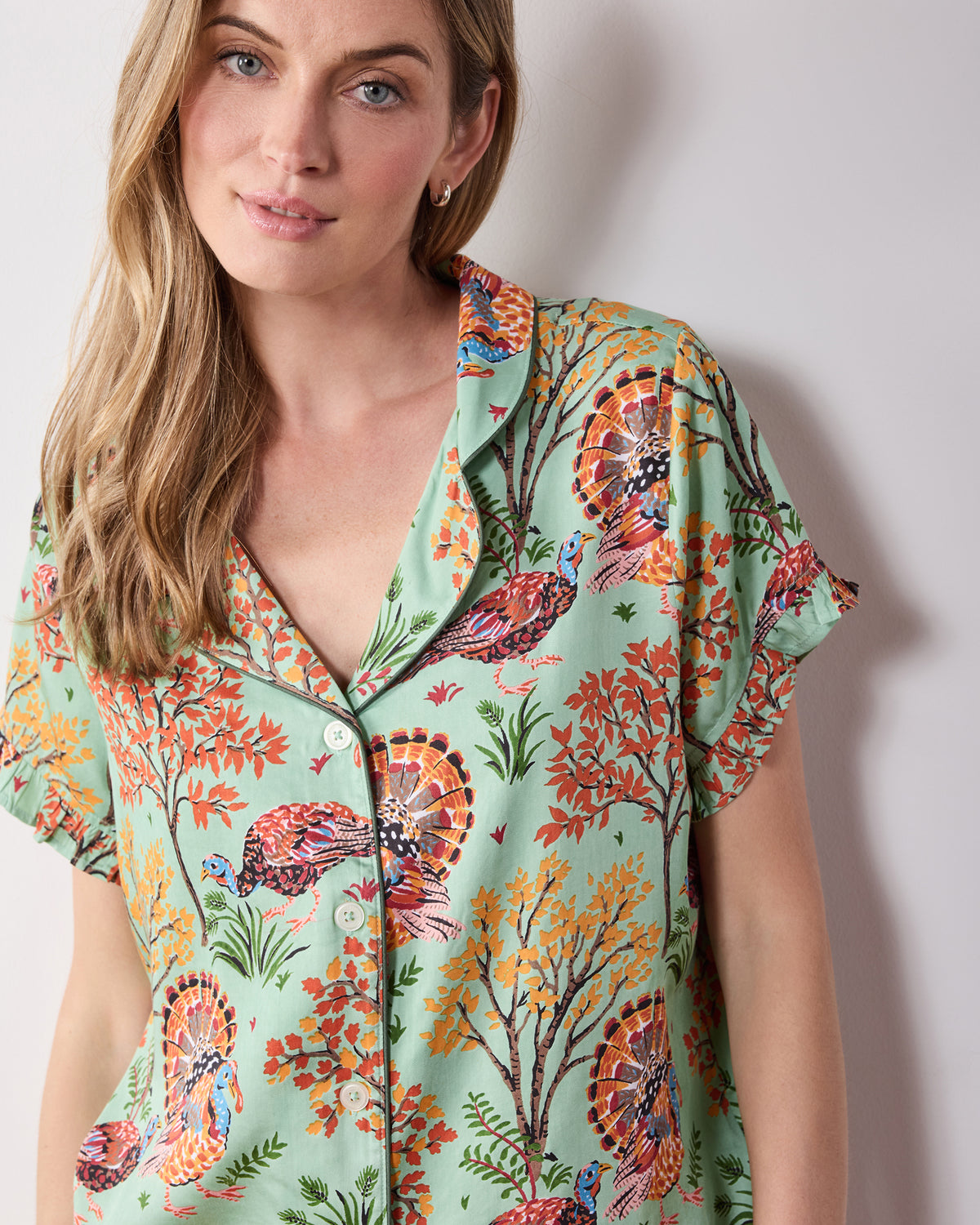 Close-up front view of the Soft Sage Turkey Trot pajama top, showing its collar, button front, ruffled sleeve, and turkey-and-foliage print.