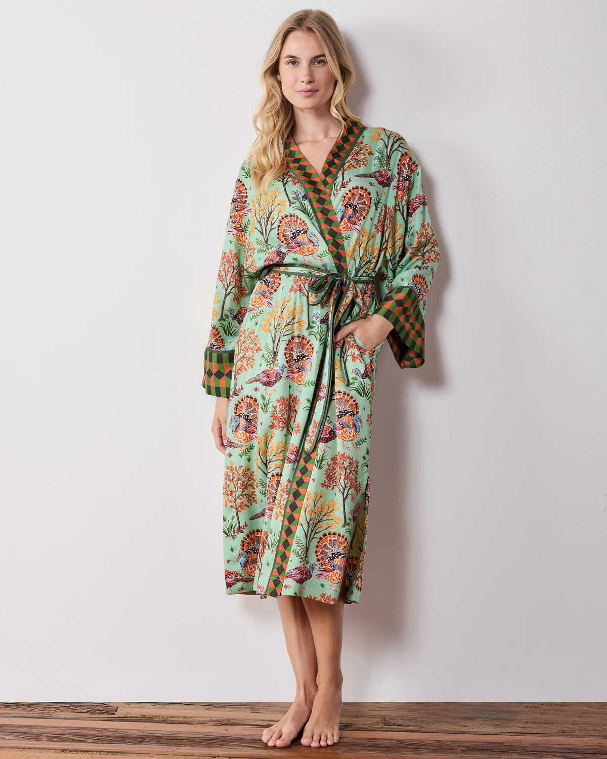 Full front view of a long soft sage Turkey Trot robe with a turkey-and-autumn-tree print, contrasting trim, tied waist, and side pockets.