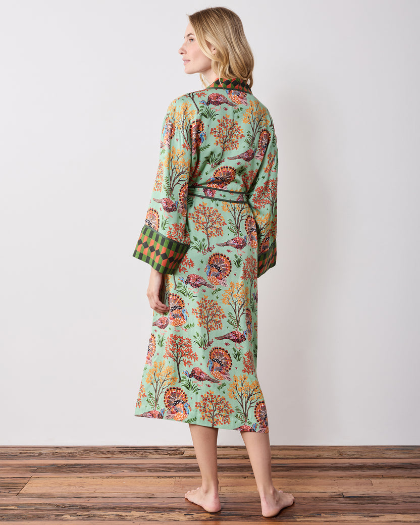 Back view of a long soft sage Turkey Trot robe with a turkey-and-autumn-tree print, tied waist, and contrasting cuffs and collar.