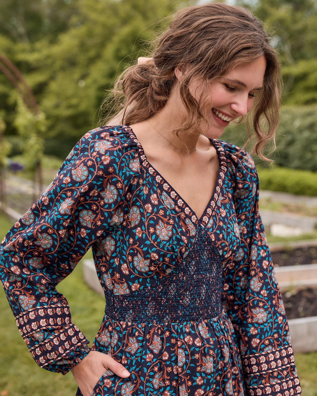 Close-up of the Valley Garden Flora Dress in Midnight Sky, showing the V-neckline, smocked bodice, floral print, and full sleeves.