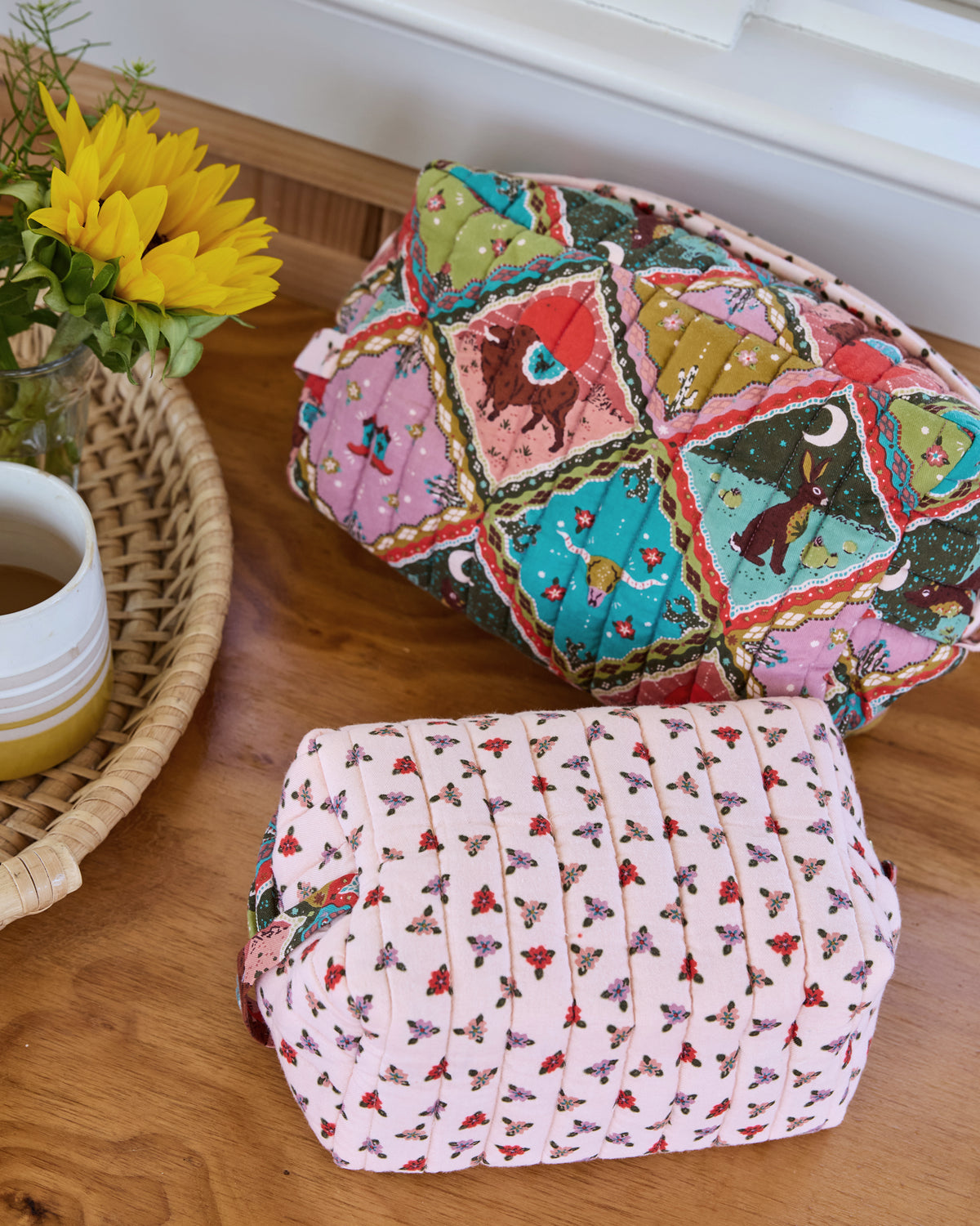 Close view of two quilted oversized pouches showing their colorful patchwork-style and floral prints.