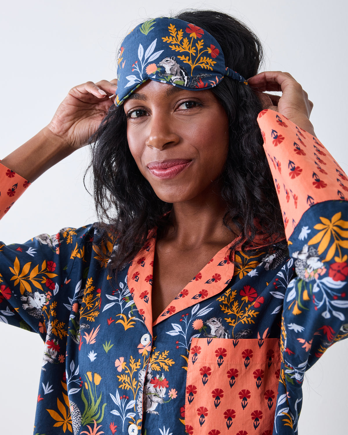 Close view of a person wearing the indigo Woodland Critters eye mask, showing the woodland print and side strap.