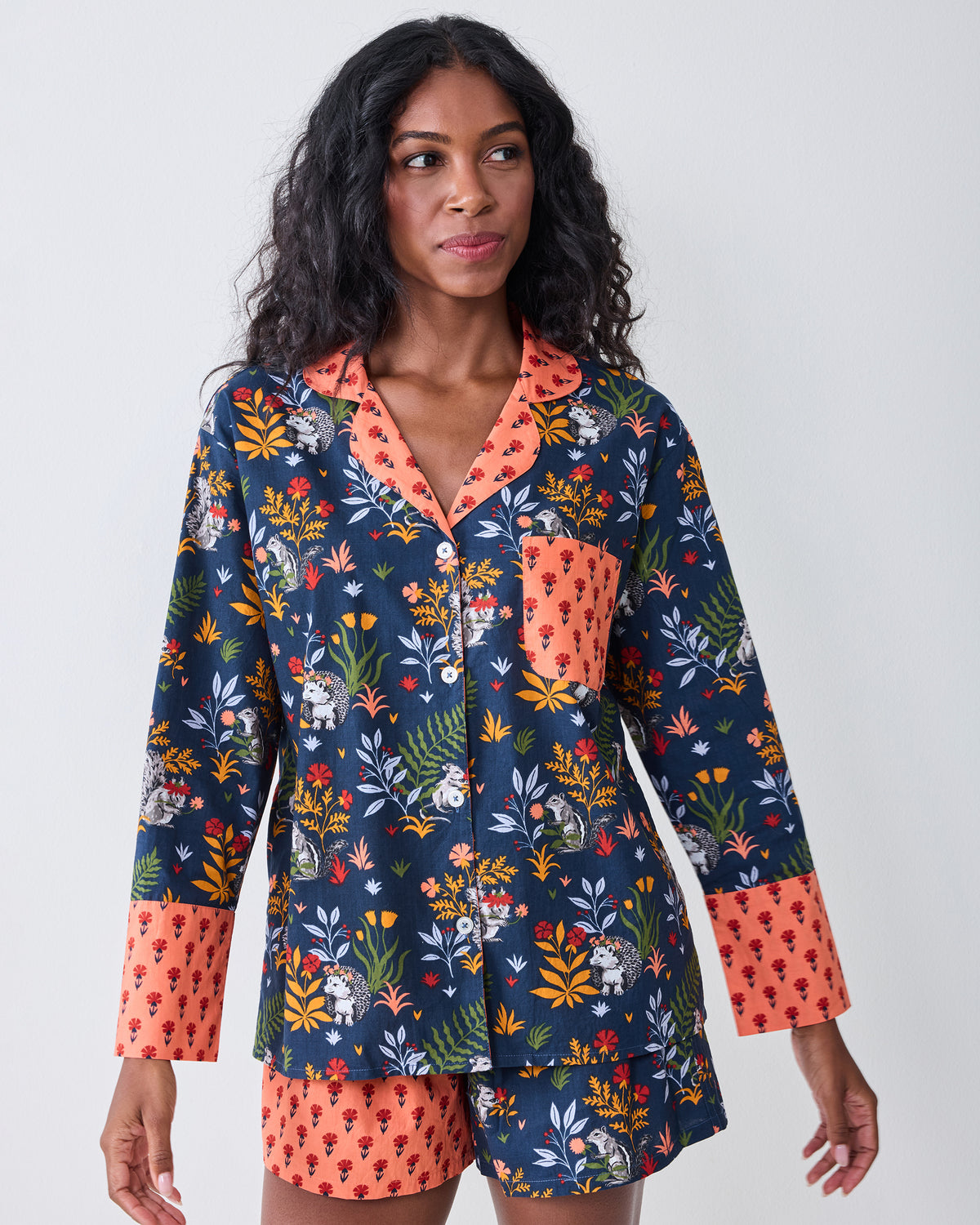 Front view of a person wearing the indigo Woodland Critters pajama set with a long-sleeve button-front top and coordinating shorts.