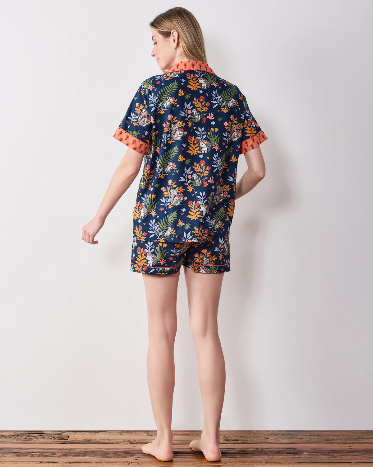 Back view of the indigo Woodland Critters short pajama set, showing the short-sleeved top, coral collar and cuffs, and matching shorts.