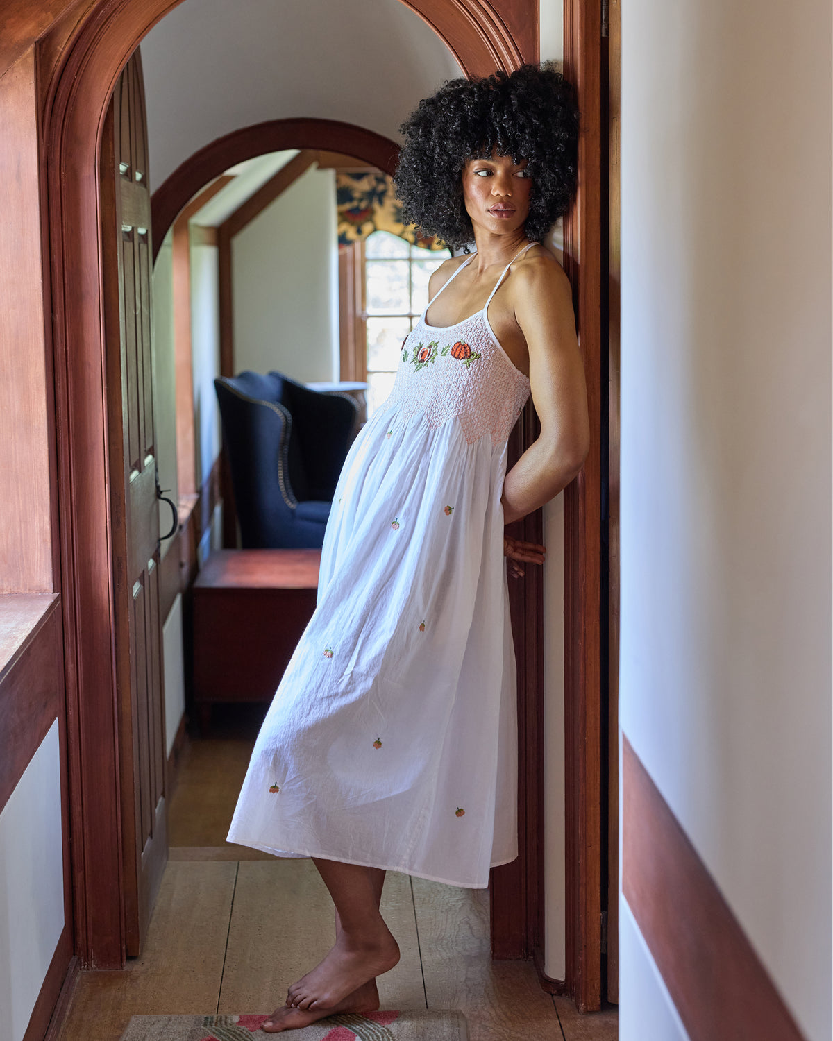 Front three-quarter view of the embroidered pumpkin Naya nightie, showing its smocked bodice, adjustable straps, and midi-length skirt.