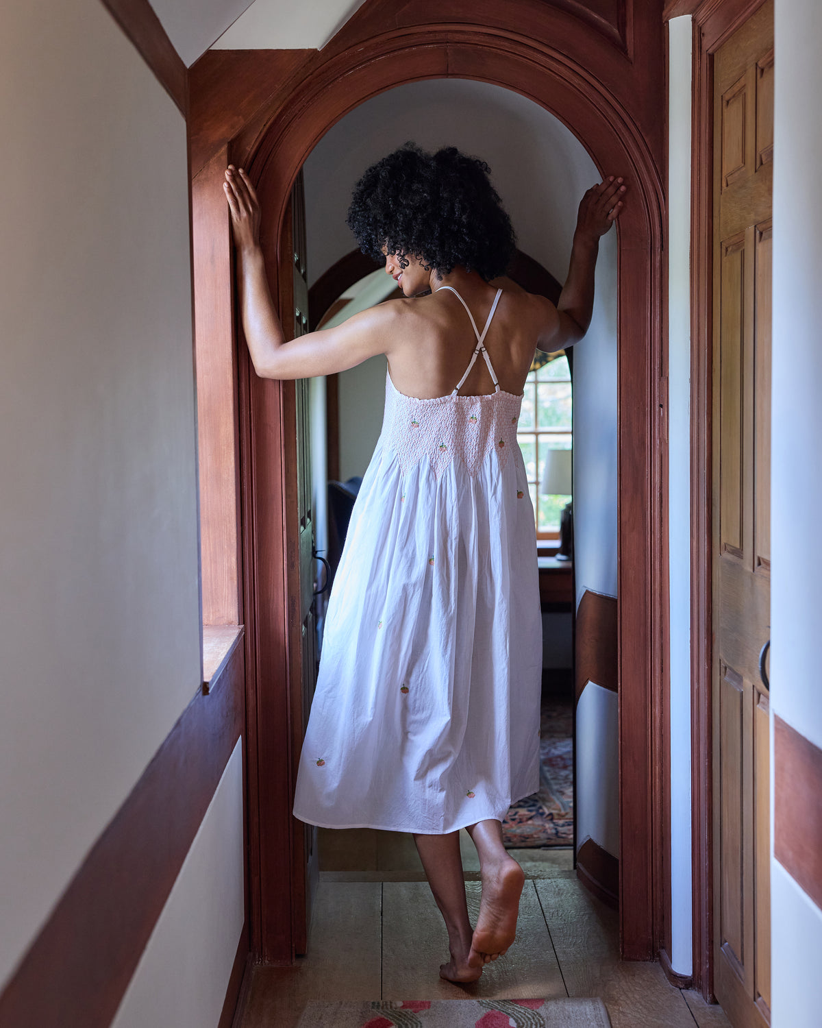 Back view of the embroidered pumpkin Naya nightie, showing crossover straps, a smocked back, and scattered embroidery.