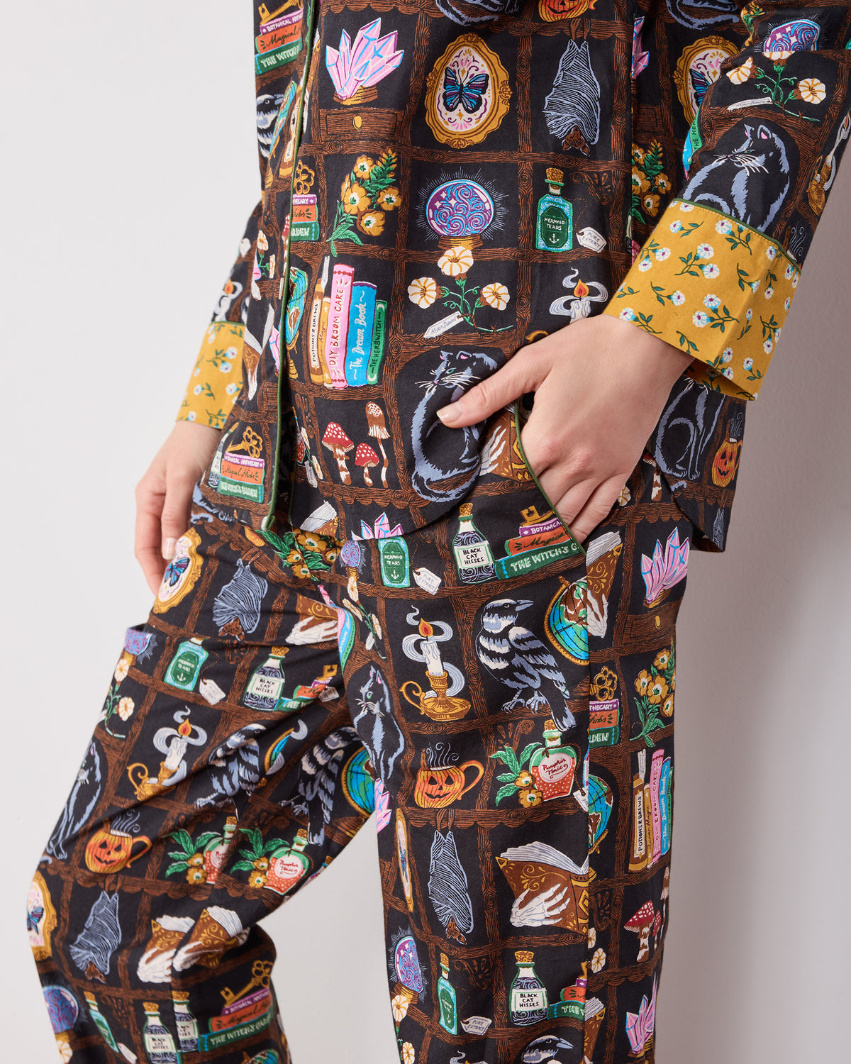 Close-up of the long pajama set showing the button-down top, front pockets, pant pocket, and contrasting mustard floral cuffs.