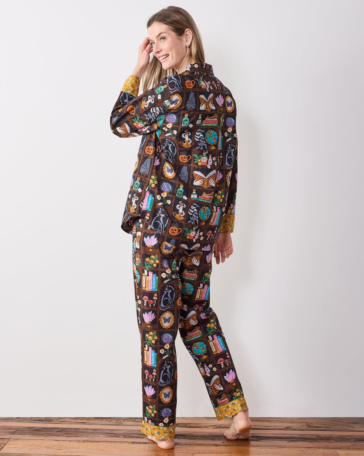 Back view of the Enchanted Study long pajama set, showing the button-down top and full-length pants in the dark illustrated print.
