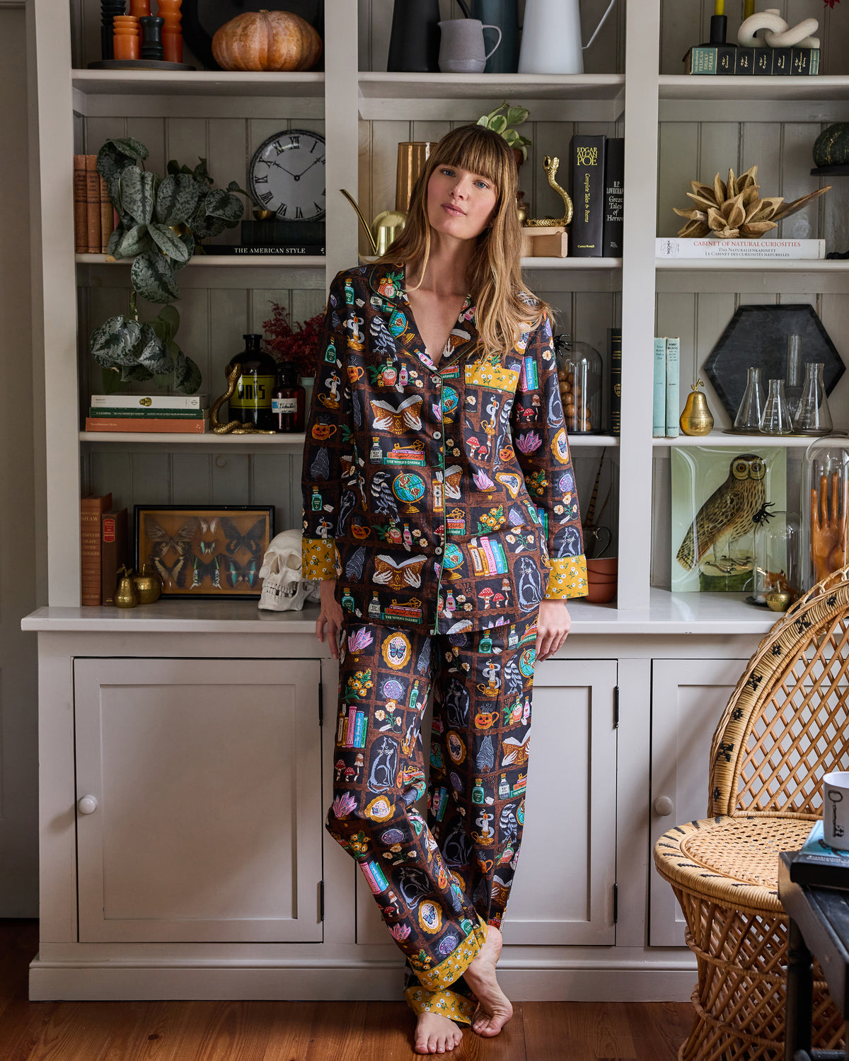Full-length view of the Enchanted Study long pajama set, showing its button-down top, long pants, and colorful cabinet-of-curiosities print.