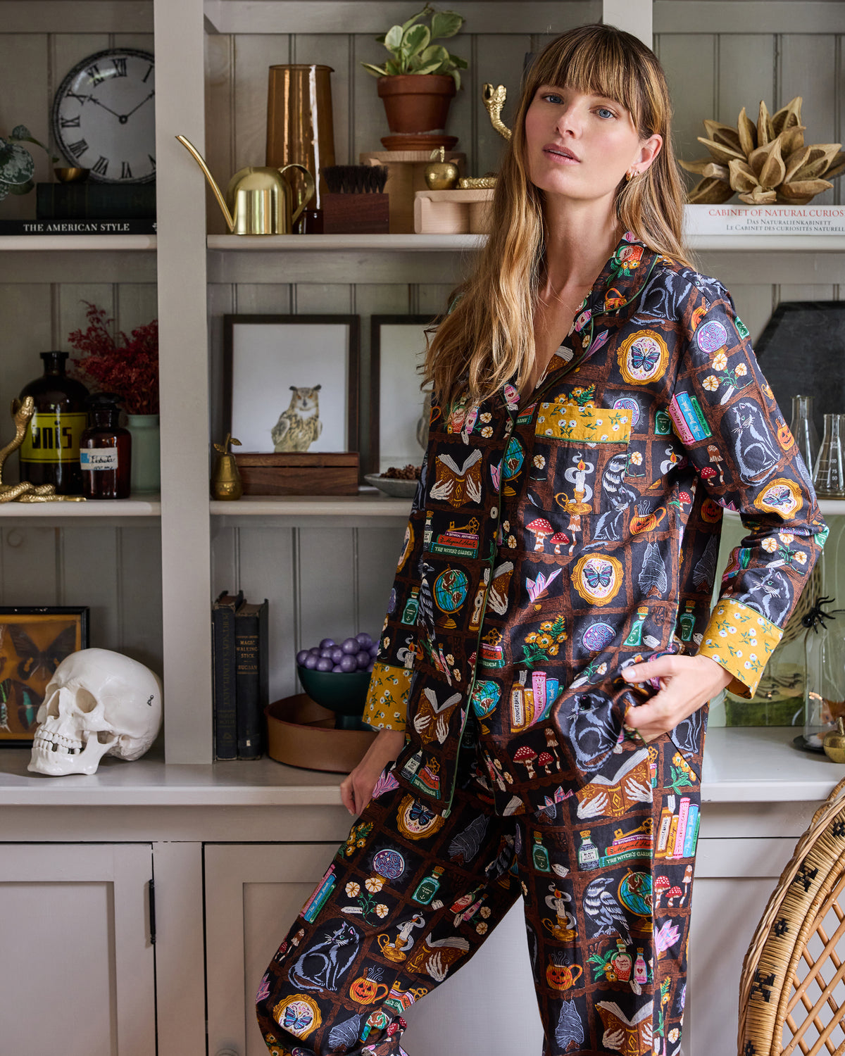 Three-quarter close view of the Enchanted Study pajama top showing its collar, buttons, patch pocket, contrasting cuffs, and illustrated print.