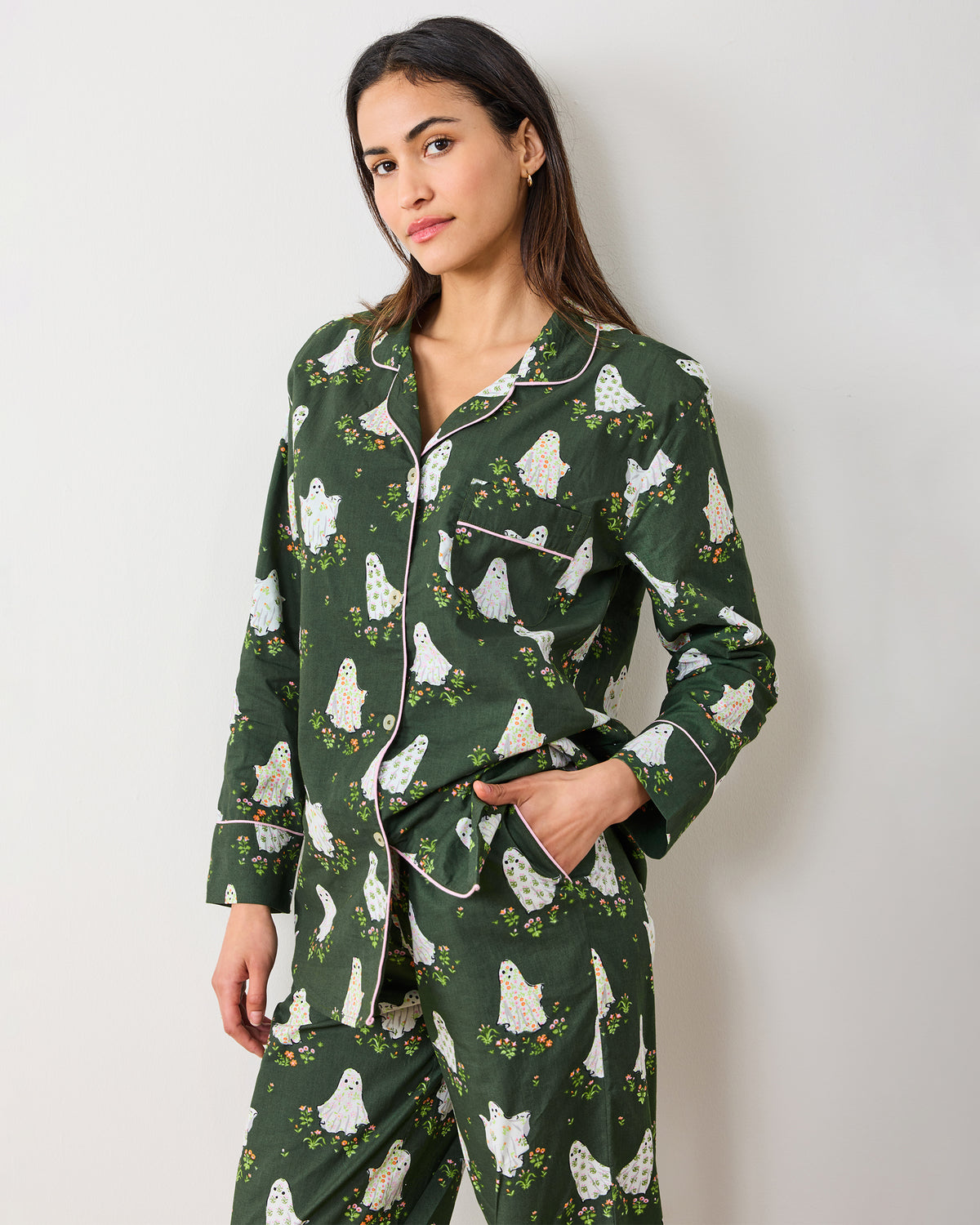 Front view of a person wearing the Gardening Ghosts petite long pajama set, with a button-front top, chest pocket, and matching pants covered in ghosts and flowers.