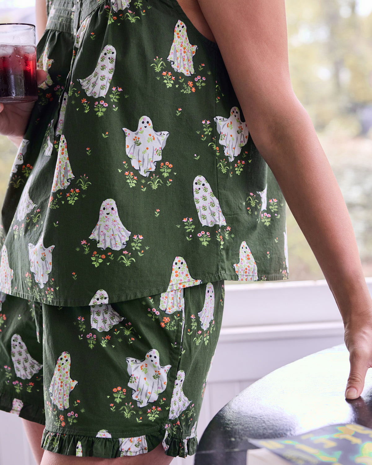 Close-up of the ghost-and-floral print on a dark green pajama top and ruffled shorts.