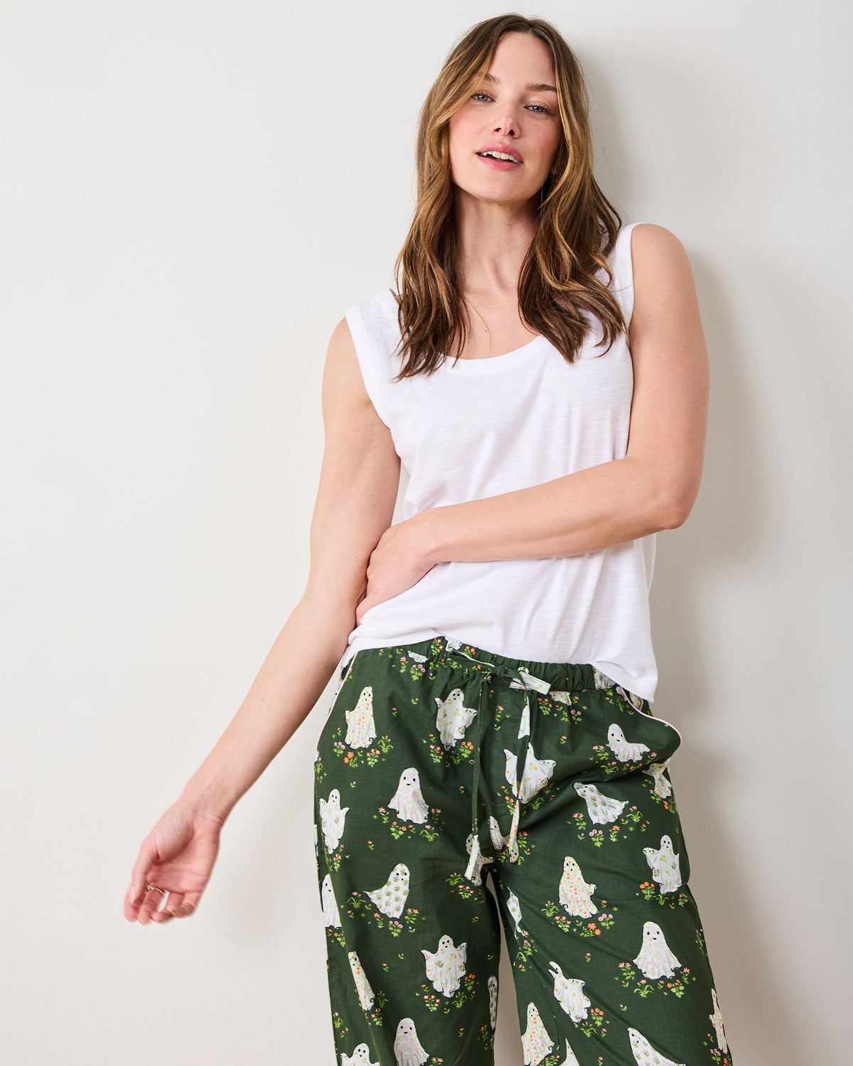 Front upper-body view of a person wearing Overgrown Moss Gardening Ghosts pajama pants, showing the drawstring waist and ghost-and-flower print.