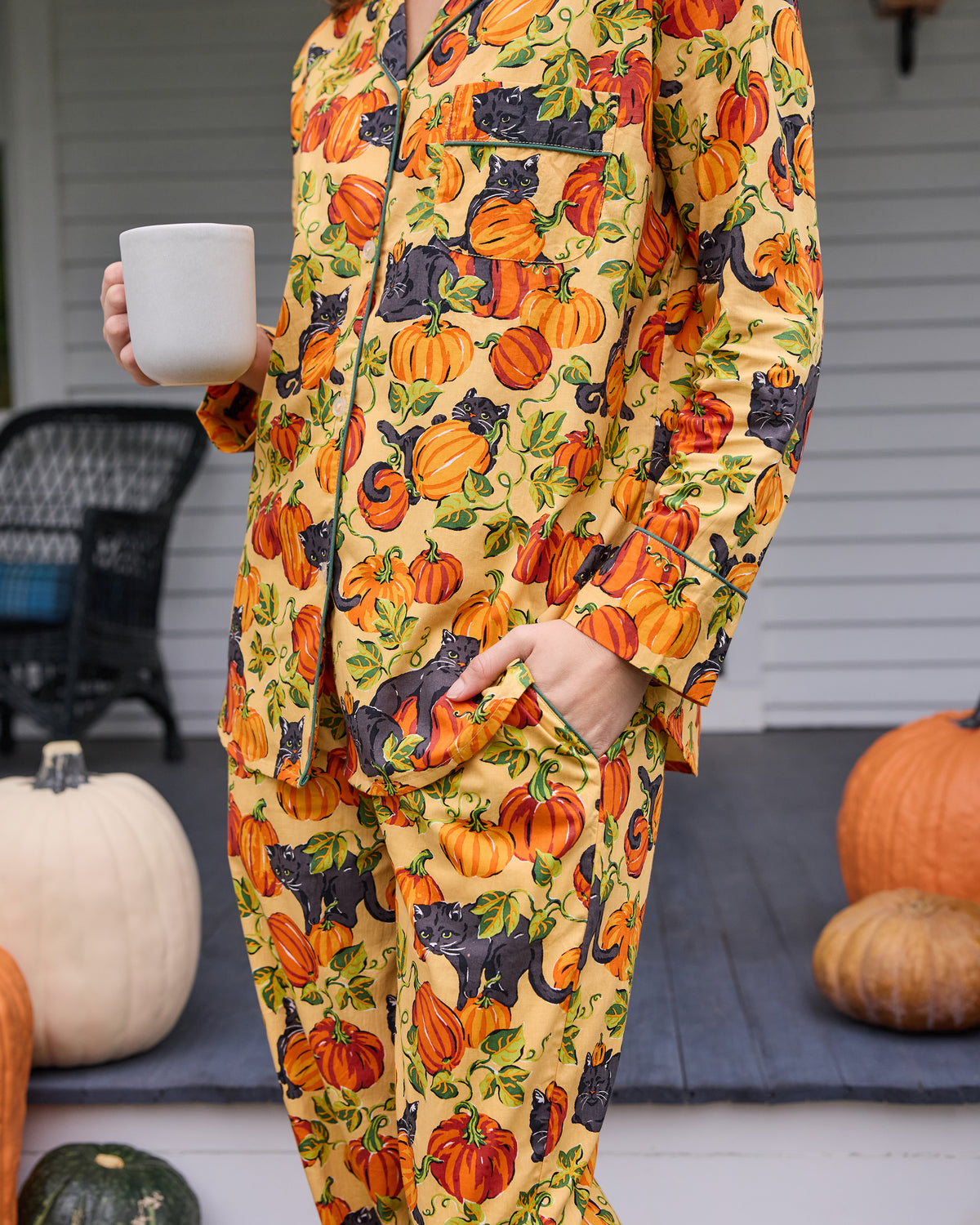 Close-up of the Pumpkin Prowl long pajama set showing the button-front top, pocket, and pumpkin and black cat print.