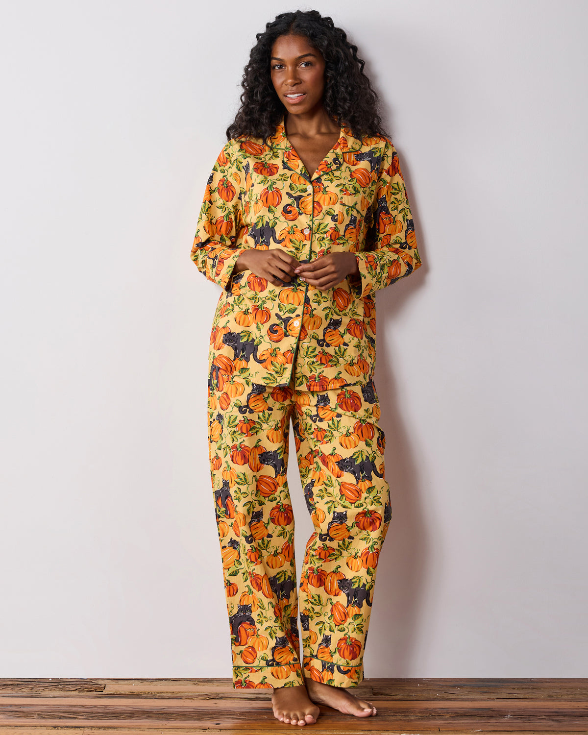 Front view of a long pajama set with a pumpkin and black cat print, button-down top, and relaxed pants.