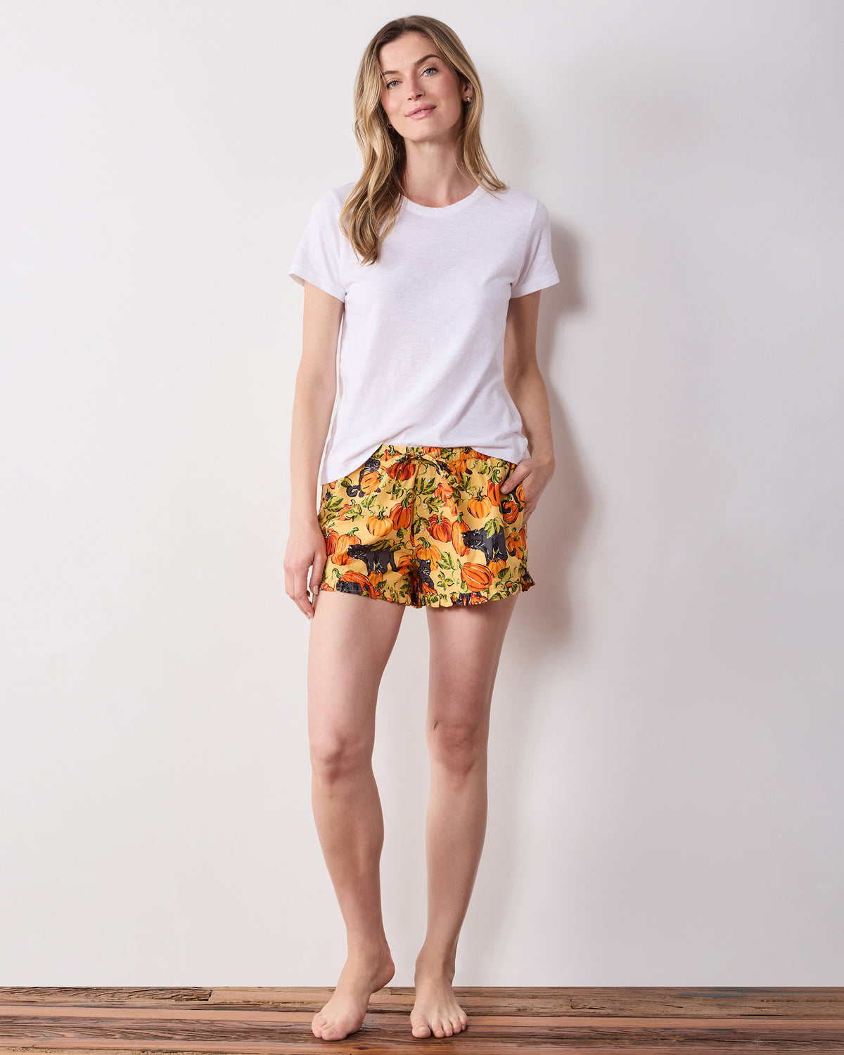 Model wearing pumpkin-print ruffle shorts with a drawstring waist and pockets.