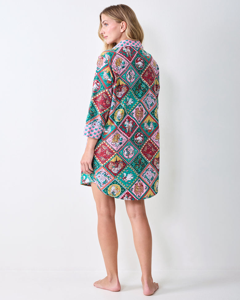 Back view of a person wearing a patterned short sleep shirt with contrasting cuffs.