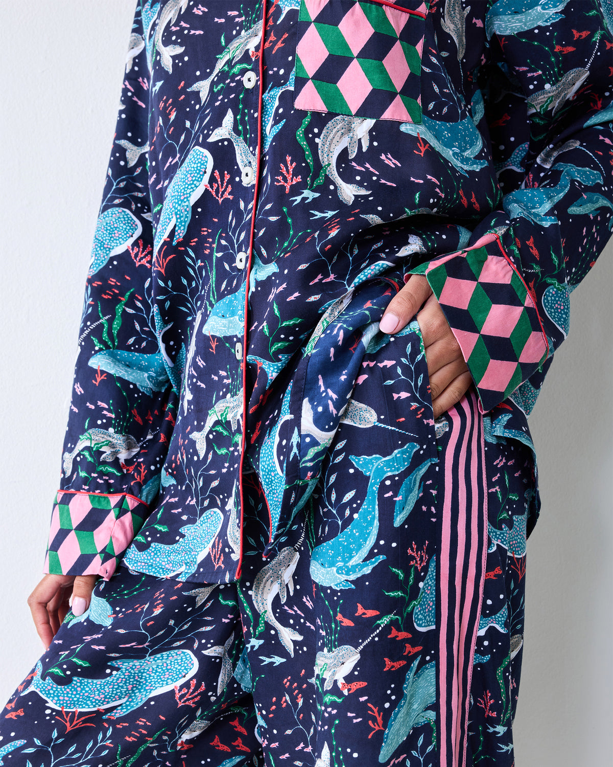 Close-up of the navy printed pajama shirt and pants showing the patterned fabric, chest pocket, cuff, and pink side stripes.