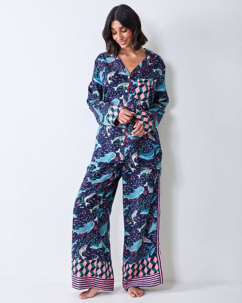 Full-length view of a person wearing a button-front Arctic Sealife pajama top and wide-leg pants with contrasting geometric cuffs and hems.