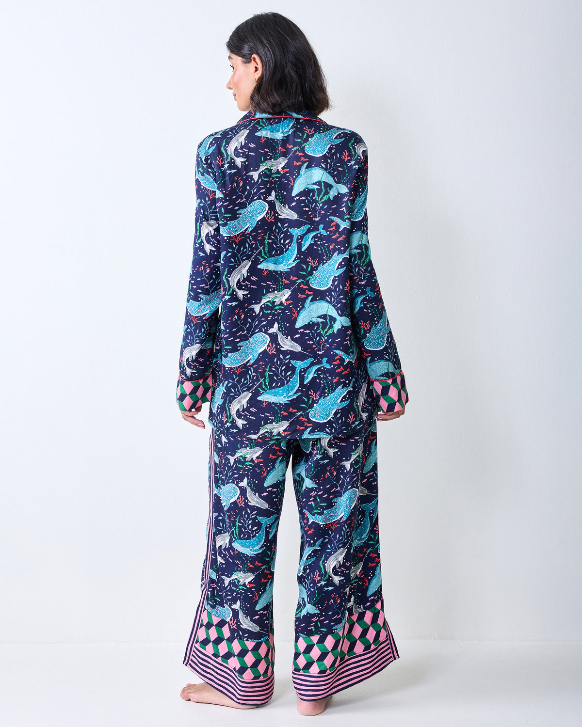 Back view of a person wearing the Arctic Sealife long-sleeve pajama set, showing the whale print and contrasting geometric cuffs and trouser hems.