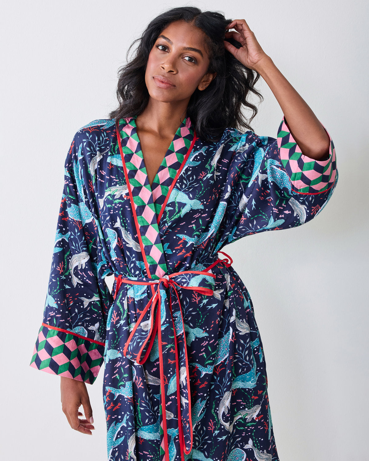 Front view of a model wearing the navy Arctic Sea Life Eco Satin Robe, showing the whale-and-underwater-flora print, contrasting geometric trim, belt, and wide cuffs.