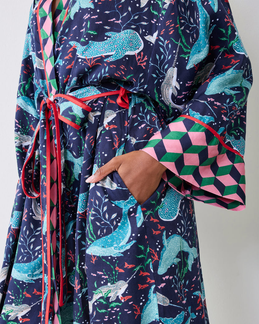 Close-up of the navy Arctic Sea Life robe showing its whale print, tied belt, contrasting geometric cuff, and side pocket.