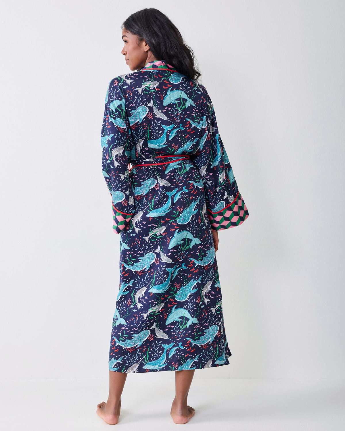Back view of a model wearing the navy Arctic Sea Life Eco Satin Robe, showing the full whale-and-underwater-flora print, belt, and contrasting cuffs.
