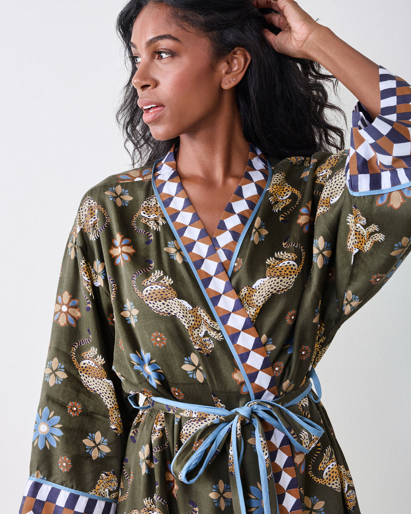 Front close-up of an olive robe with leopard and floral print, contrasting geometric trim, wide sleeves, and a tied belt.