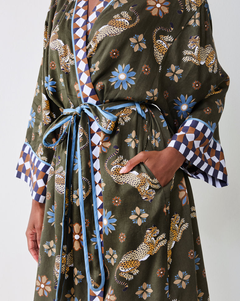 Close-up of the olive robe's waist and skirt showing the tied belt, geometric trim, leopard and floral print, and side pocket.
