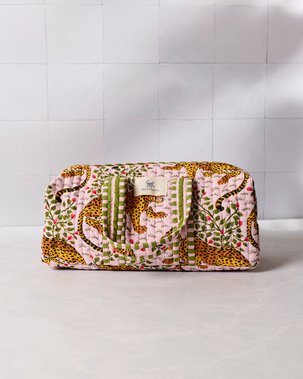Closed pink leopard-print quilted hair tool travel case with green striped handles