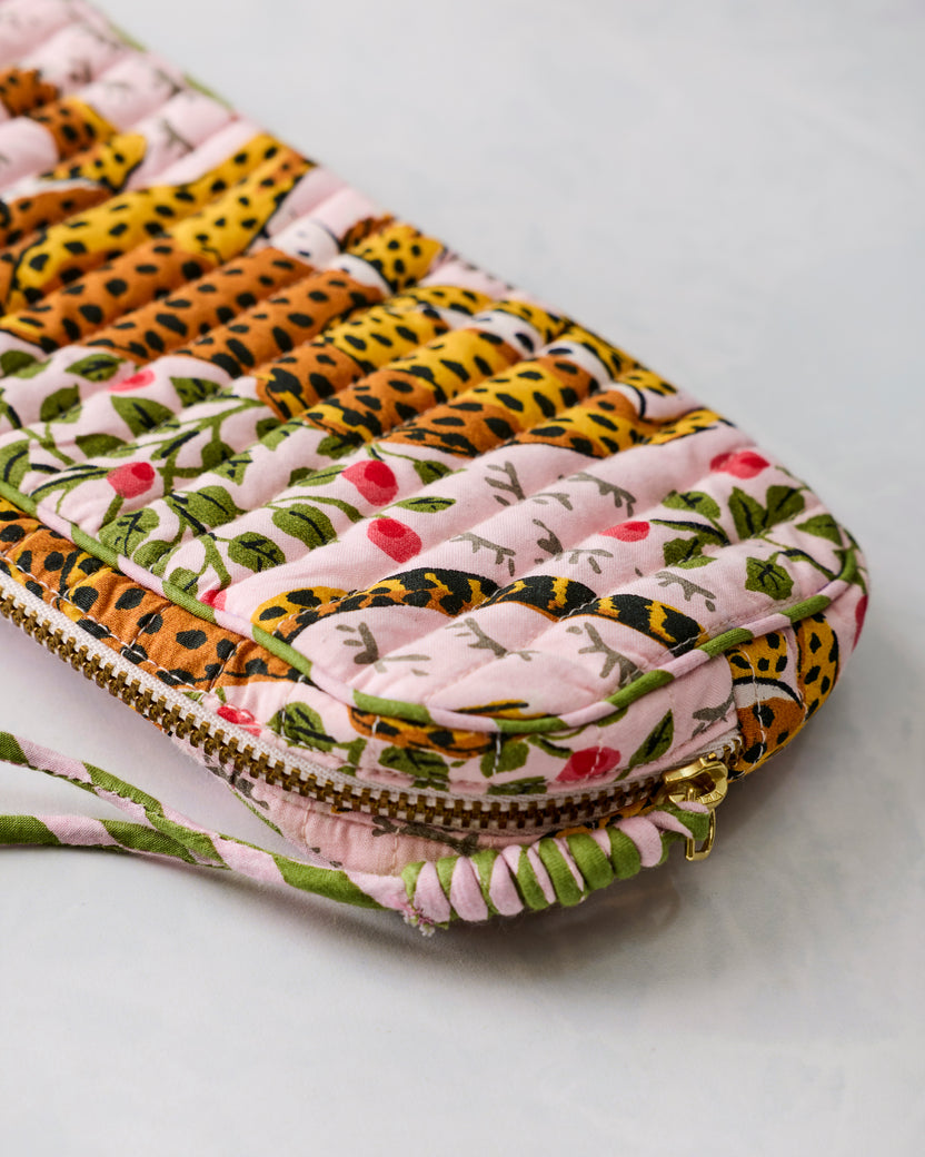 Close-up of the pink quilted sunglasses case showing its zipper, green trim, and leopard-botanical print