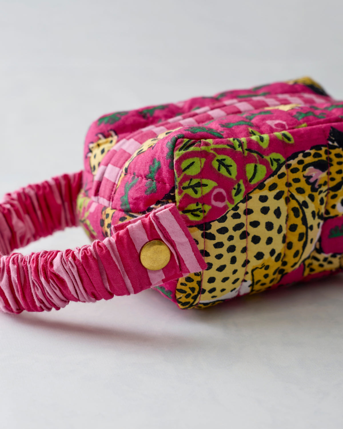Hot pink quilted wristlet with leopard print, zipper, and ruched wrist strap shown from the side.