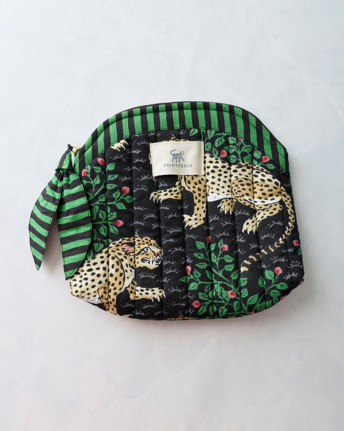 Bagheera Ink quilted makeup bag with leopard-and-leaf print, striped trim, wrist loop, zipper, and Printfresh label.