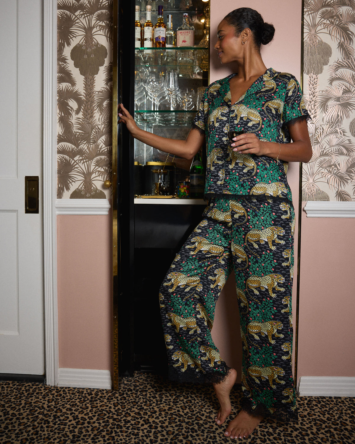 Person standing in the Bagheera Eco Satin Jackie Set, showing the short-sleeved button-front top and wide-leg pants in a leopard-and-foliage print.
